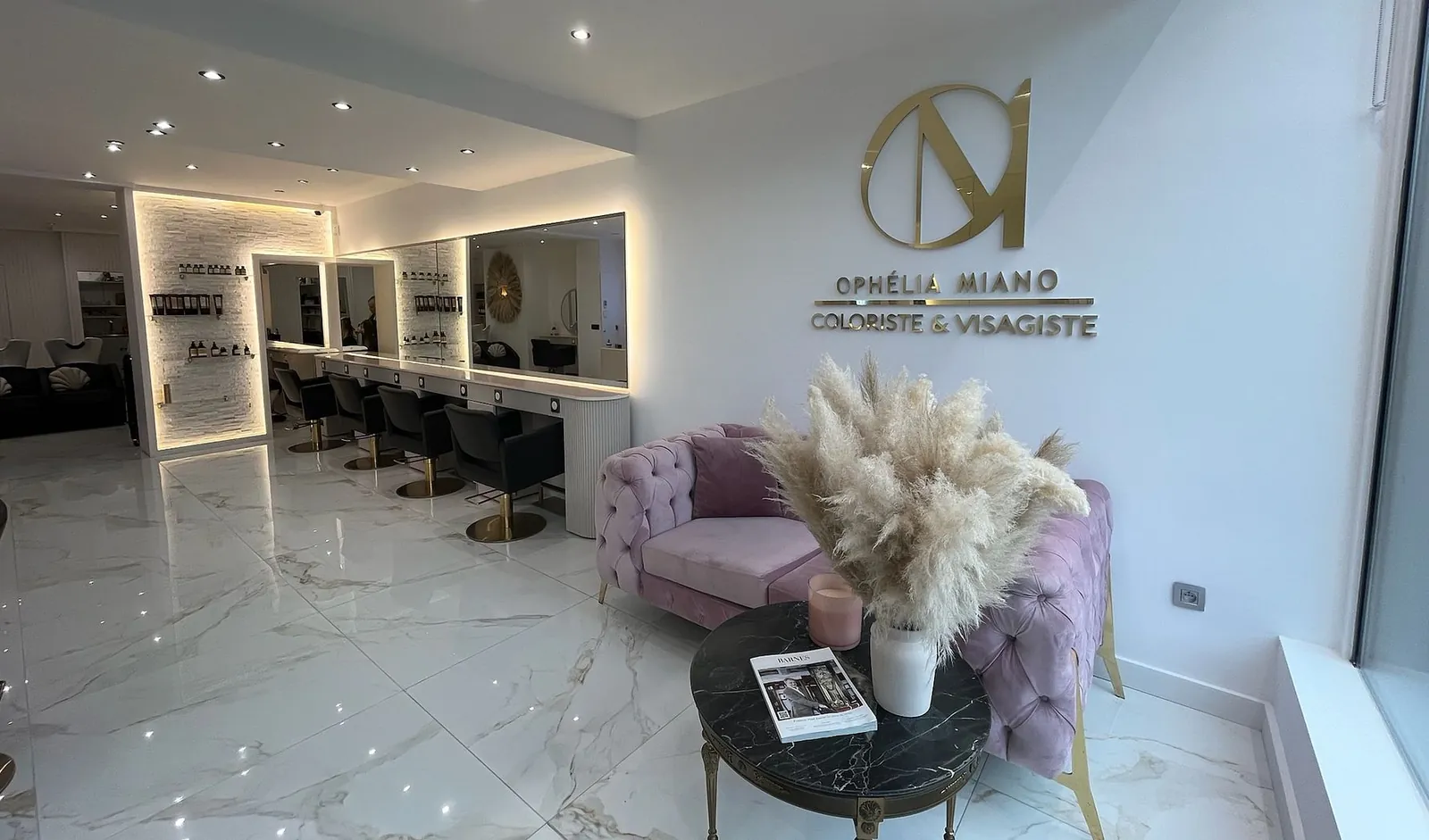 L’entrée du salon, son canapé rose poudré et le logo doré